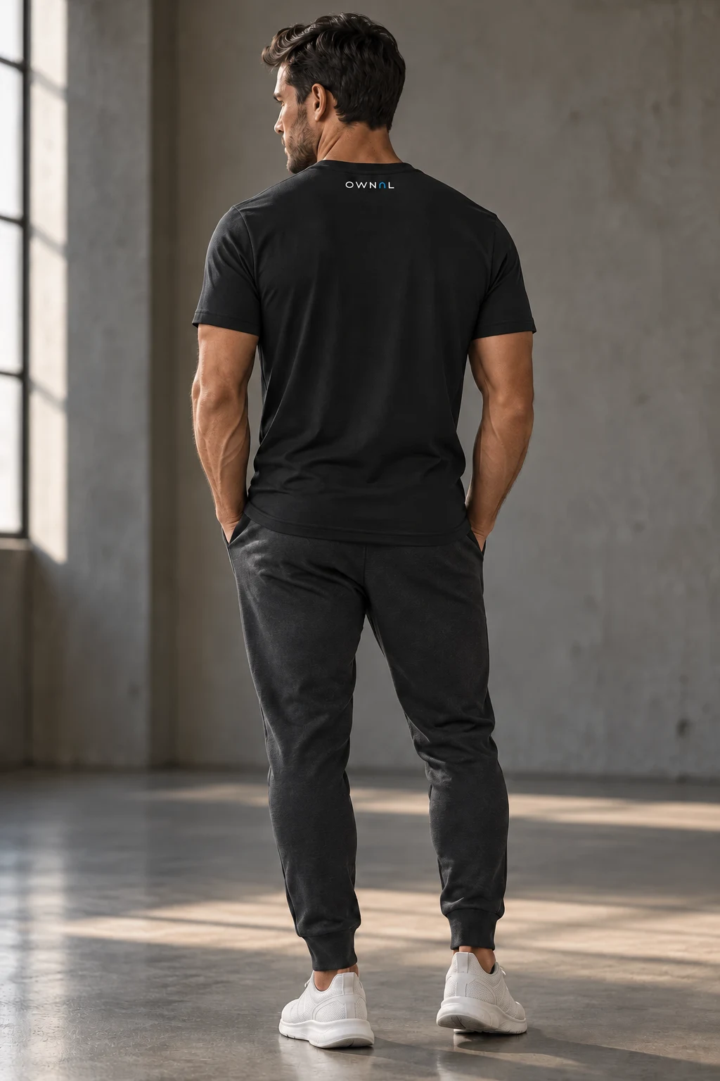 Rear view of a black OWNAL tee on a male model