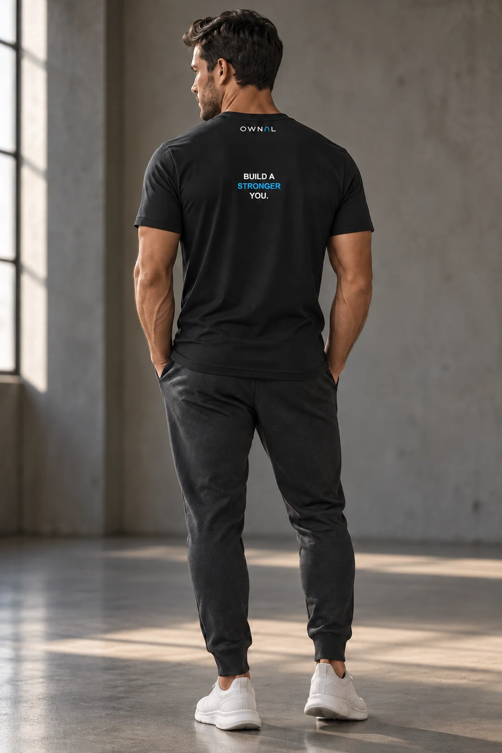 Male model showing a small BUILD A STRONGER YOU back print on a black OWNAL tee