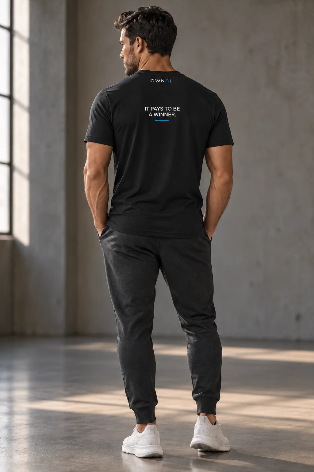 Male model with a small IT PAYS TO BE A WINNER back print on a black OWNAL tee